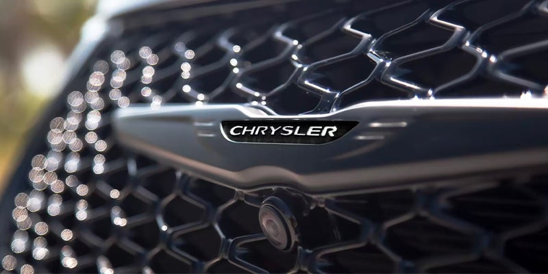 Close-up of a Chrysler logo on the front grille of a car.