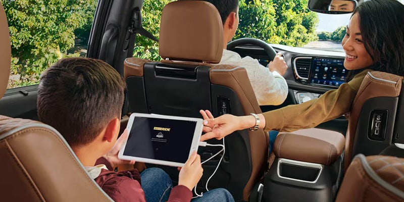 Family enjoying a connected SUV interior with rear-seat entertainment and modern touchscreen technology during a drive.
