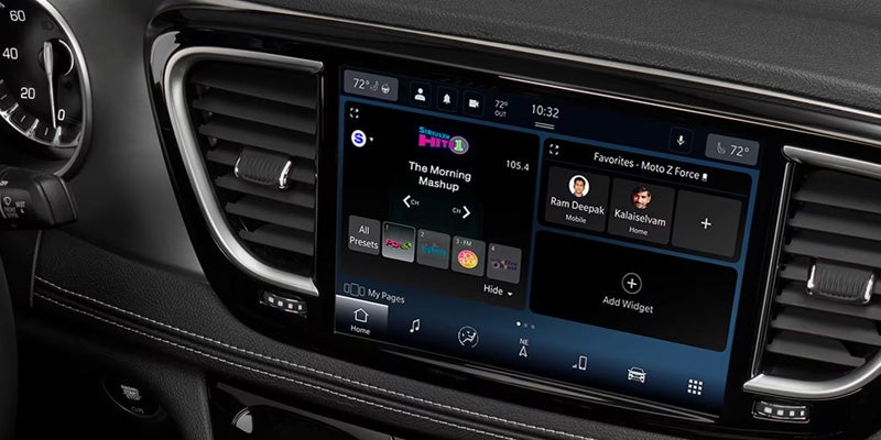 A dashboard of a Chrysler Pacifica displaying an infotainment system with a touchscreen interface, showing options for radio stations and the current temperature.