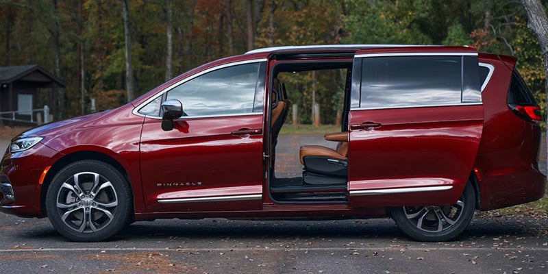 Red Chrysler Pacifica with power sliding doors open, showcasing easy passenger access and a spacious interior.