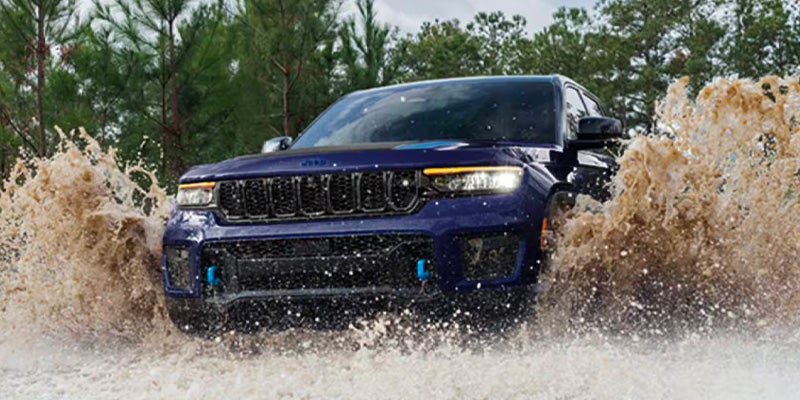 Grand Cherokee splashing through muddy water trail