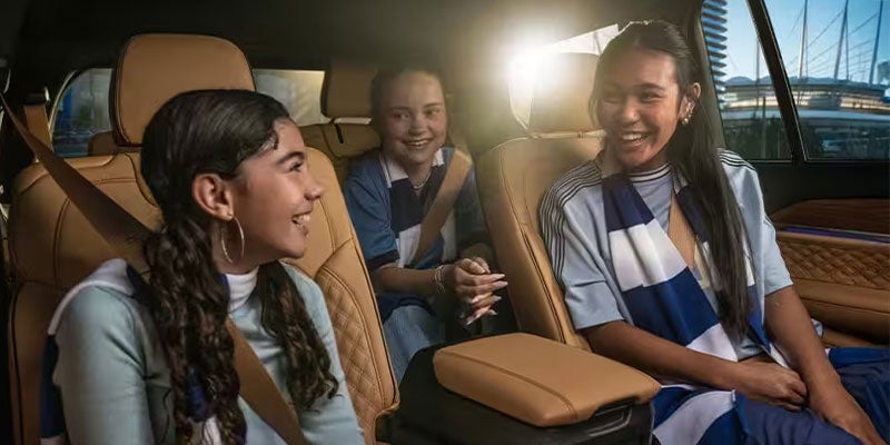 Three young women sitting in a car, smiling and enjoying each other's company.