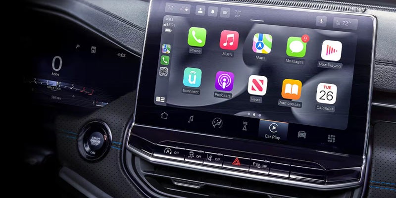 Car dashboard showing digital speedometer and infotainment screen displaying Apple CarPlay apps including Phone, Music, Maps, and Messages.