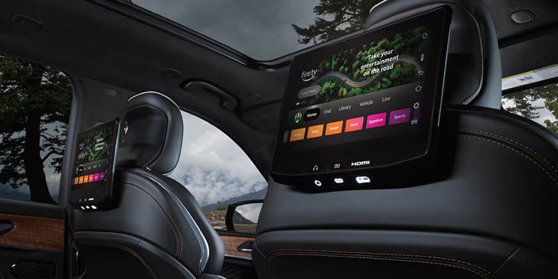 Interior of a car featuring two touchscreen displays mounted on the backrests of the front seats.