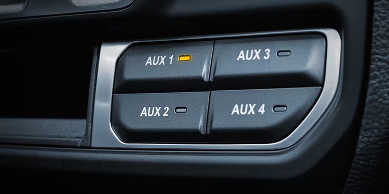 Four buttons labeled AUX 1, AUX 2, AUX 3, and AUX 4 on a car console.