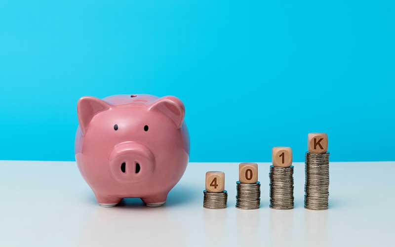 Pink piggy bank beside stacked coins spelling