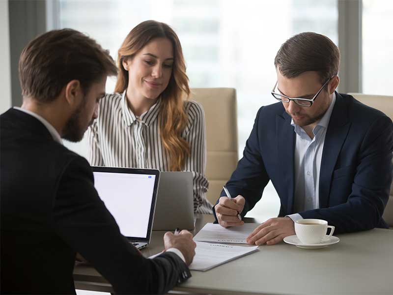 Three professionals in business attire collaborating in a modern office setting.